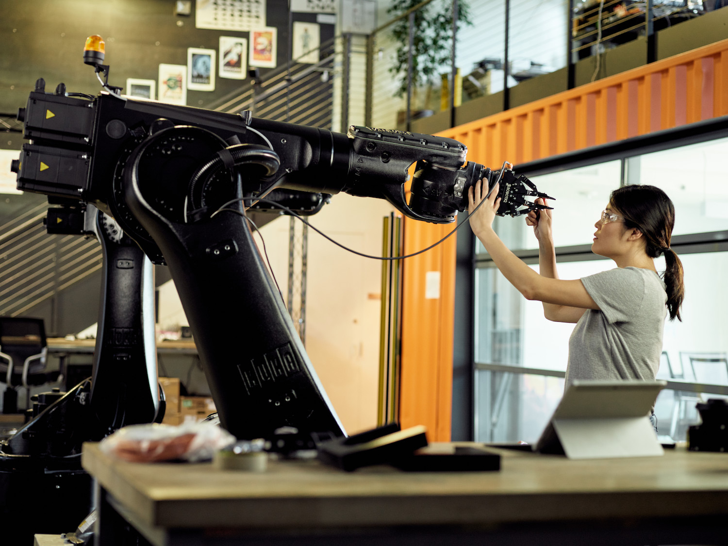 一个女人在实验室里触摸着一个巨大的机械手臂。
