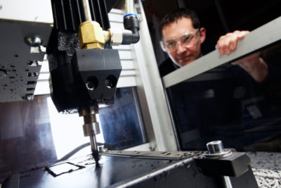 man watching CNC mill while wearing safety glasses safe